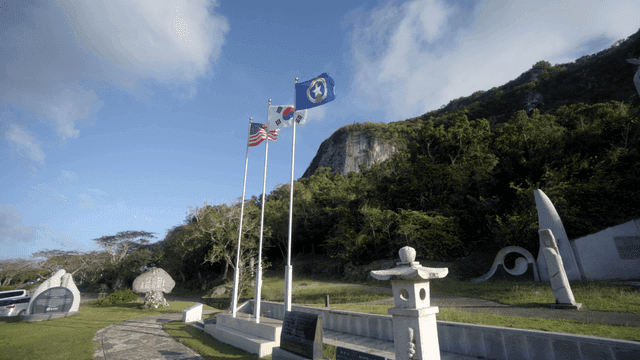 기념비 앞에서 펄럭이는 미국, 한국, 북마리아나제도 국기