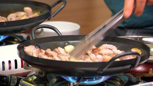 팬에 마늘과 삼겹살을 요리하는 장면