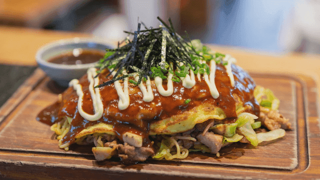 Okonomiyaki topped with sauce and seaweed
