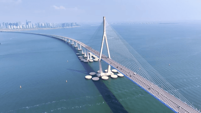 A long bridge over a vast sea with a city skyline