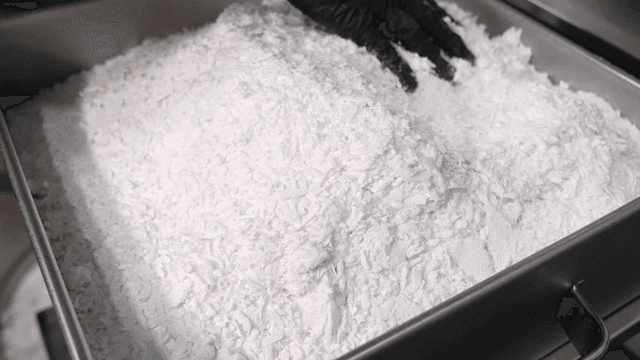 Person pouring white rice flour into metal steamer