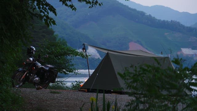 Tents and motorbikes at a lakeside campsite at sunset