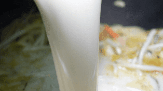 Pouring broth into a pot with vegetables