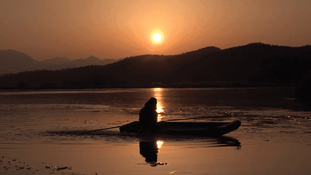 Person splashing water in calm river and sunset