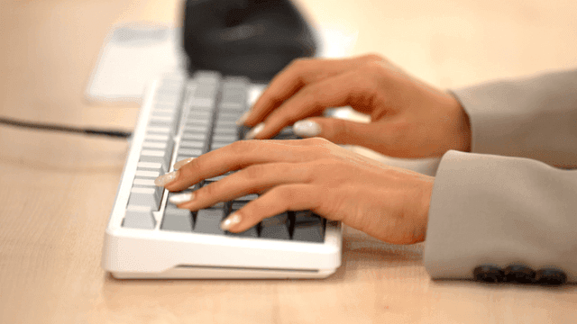 Hand of female office worker typing on keyboard in office