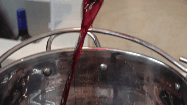 Red wine bottle poured into large pot