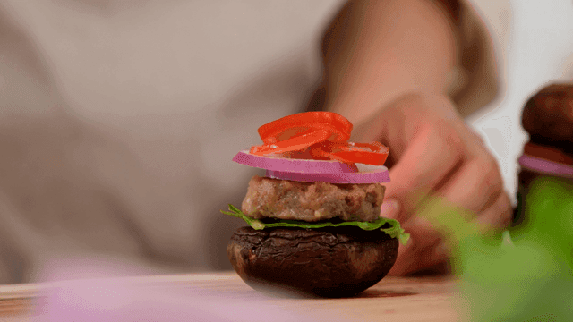 Hands assembling mushroom burger with fresh ingredients