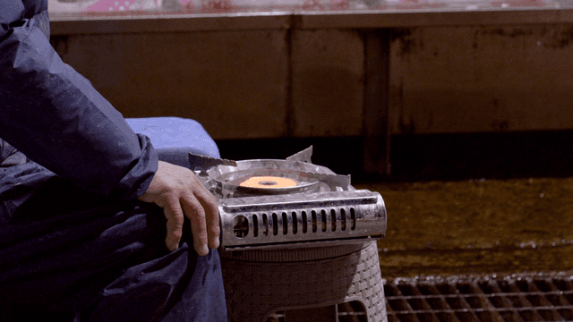 Person warming their hands on gas burner