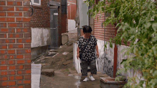 골목길을 걷는 노인 여성