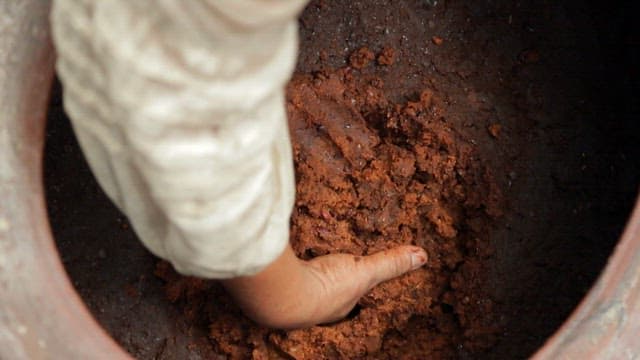 Hand mixing fermented soybean paste in a jar