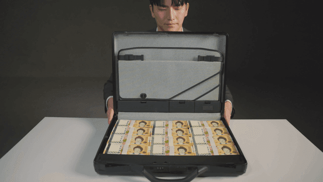 돈이 가득한 서류 가방을 보여주는 남자