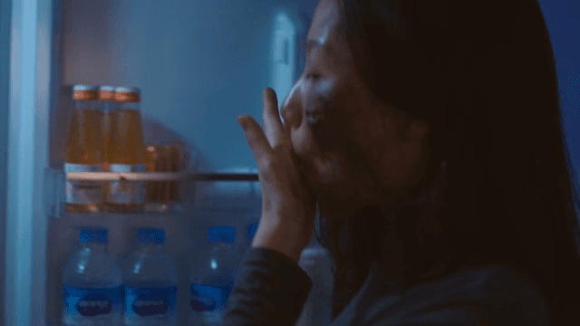 얼굴에 상처가 난 여성이 냉장고 속 음식을 허겁지겁 먹는 모습