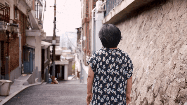 Back view of an elderly woman blankly looking at an alley