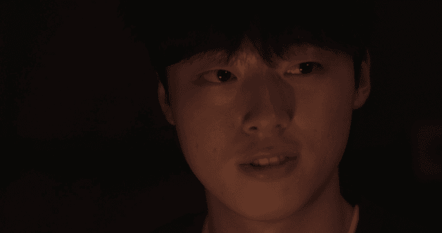 Young man closing his eyes to light in dark room