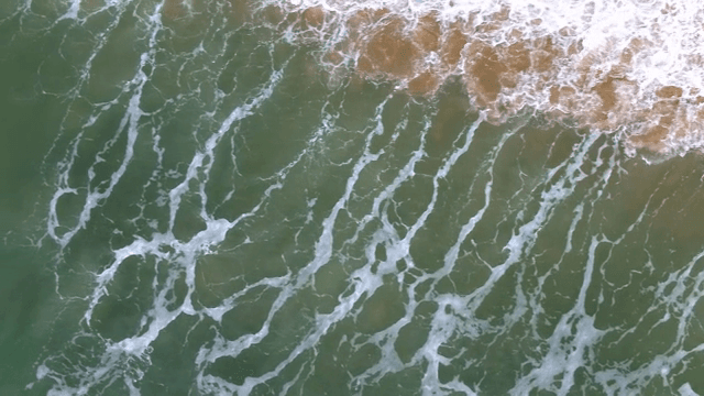 모래 해변에 부딪히는 잔잔한 파도