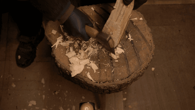 Wood carving on a tree stump in workshop