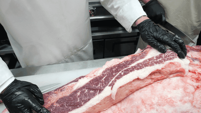 Butcher cutting large beef in meat shop