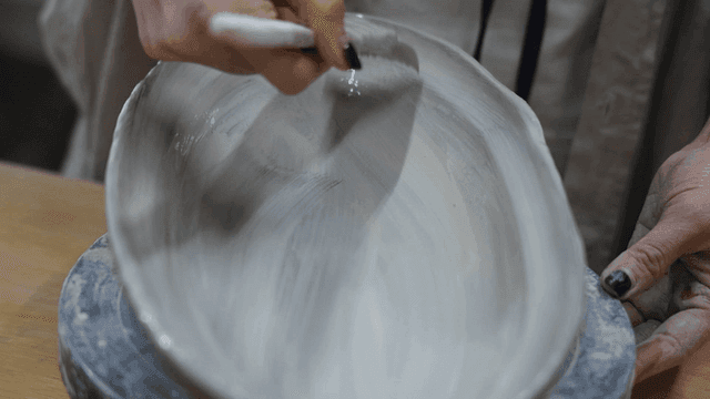 A person applying glaze to pottery