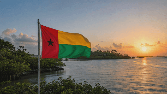 Guinea-Bissau flag fluttering on seashore at sunset