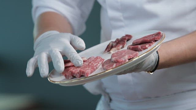 셰프가 신선한 소고기를 담은 접시를 보여주는 장면