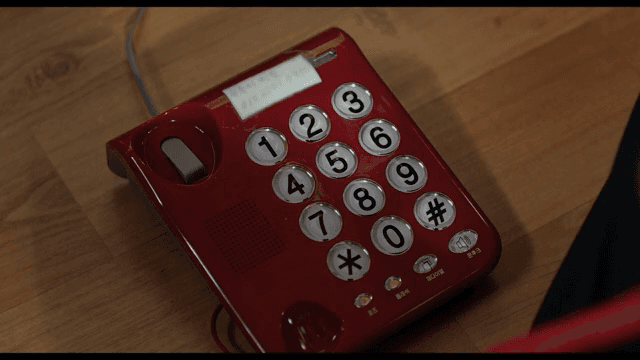 빨간 전화기의 버튼을 누르는 손