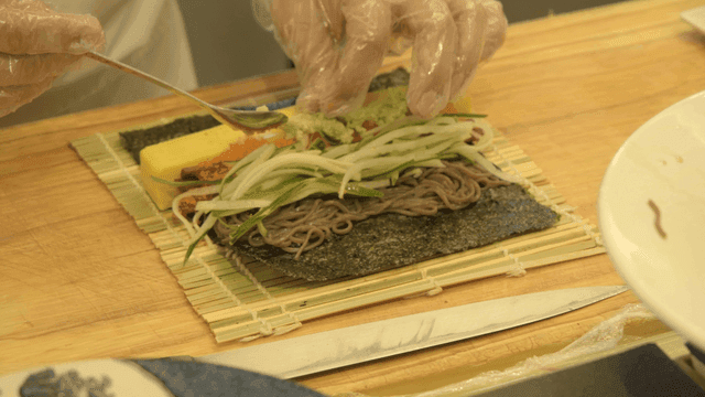 Chef preparing sushi rolls with various ingredients