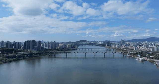 Wide river flowing under bridge connecting modern city