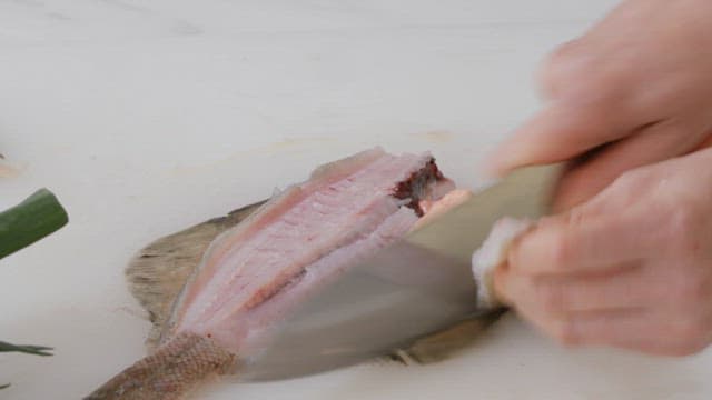 Fresh fish being prepared with a knife on a cutting board