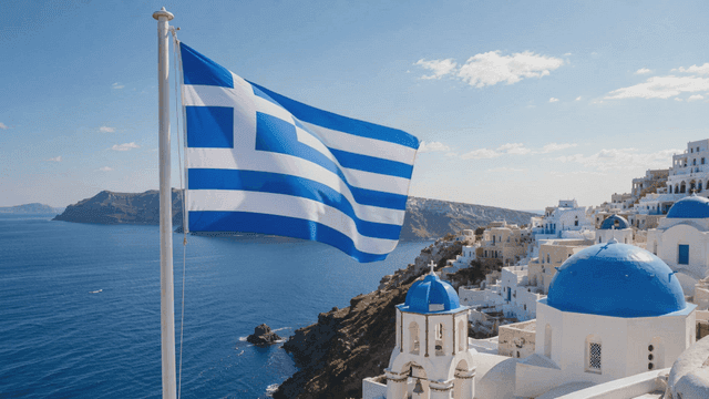 Greek flag waving over a coastal town