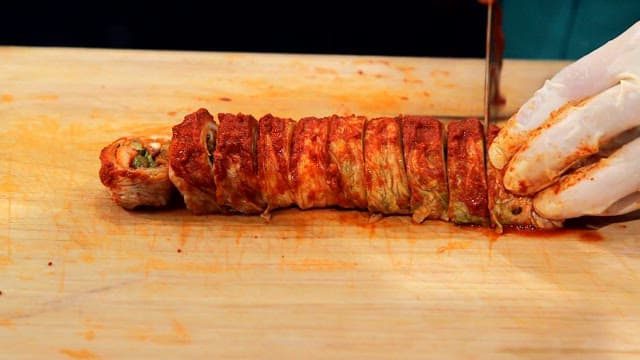 Slicing kimchi rolls on a cutting board