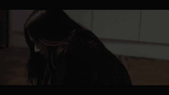A woman sitting on the floor in a dimly lit room