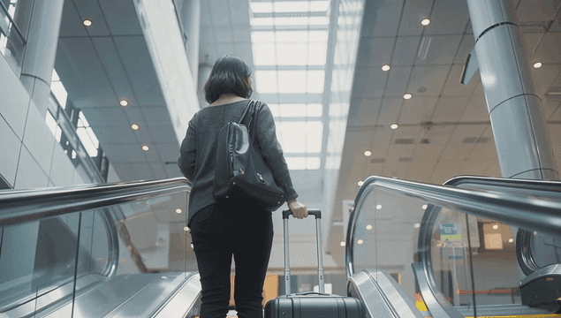 A woman with luggage on an escalator