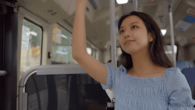 손잡이를 잡고 버스를 타는 여성