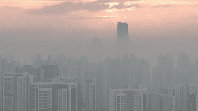 Sunrise over a city skyline with haze