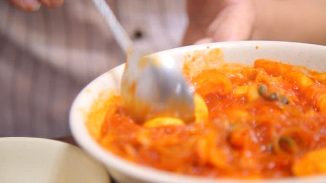 Spoonful of egg in a bowl of spicy tteokbokki