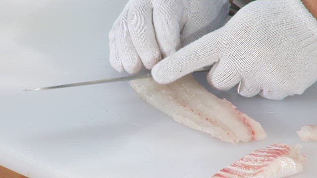 Slicing raw fish delicately with a knife on a cutting board