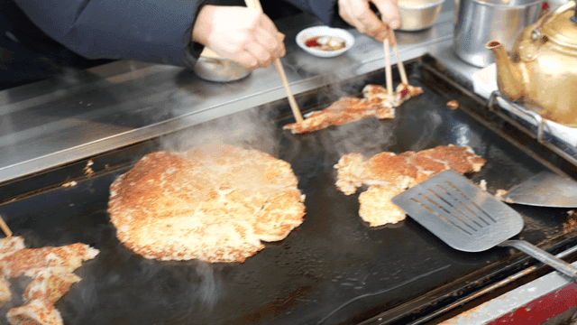 People eating potato pancakes grilled on hot iron plate