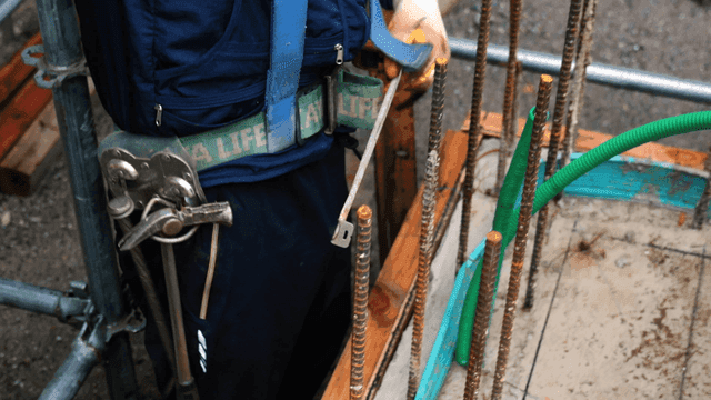 건설 현장에서 철근을 측정하는 작업자