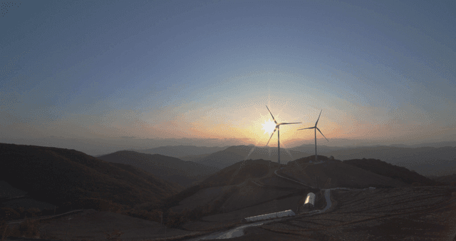 Brilliant sunrise beside wind turbines on the hill farm