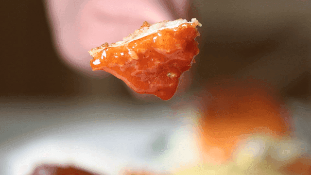 Fork lifting pork cutlet drizzled with sauce