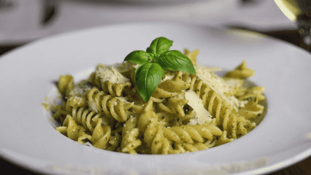 Plate of fusilli pasta topped with basil.