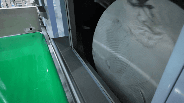 Pile of white fabric entering large rotating machine