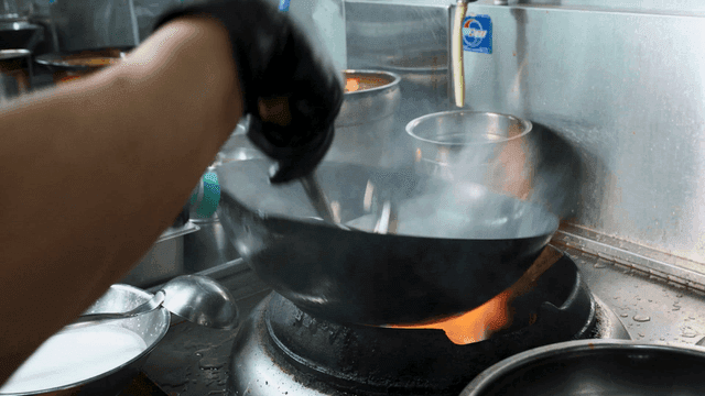 Chef cooking with wok over hot fire