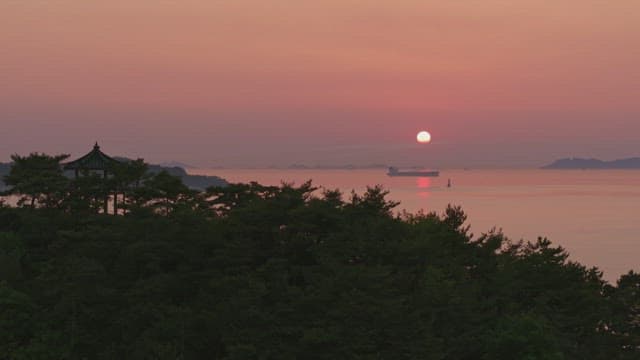 오래된 정자가 있는 바다 위의 일몰