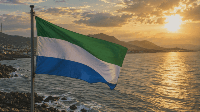 Sierra Leone flag fluttering by sea at sunset
