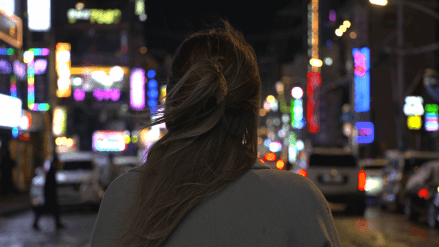 Back view of woman on lively night city street