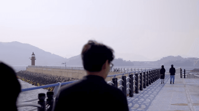 등대가 있는 부두를 걷는 사람들