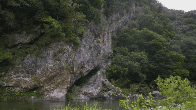 Quiet river flowing beside rocky cliff