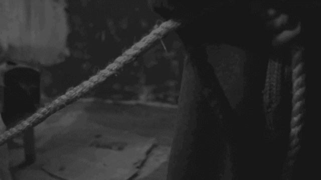 어두운 실내에서 누군가에 의해 밧줄에 묶여있는 사람