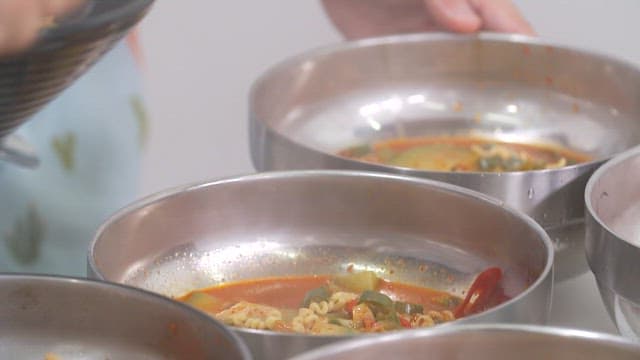 Serving spicy dumpling soup in a metal bowl